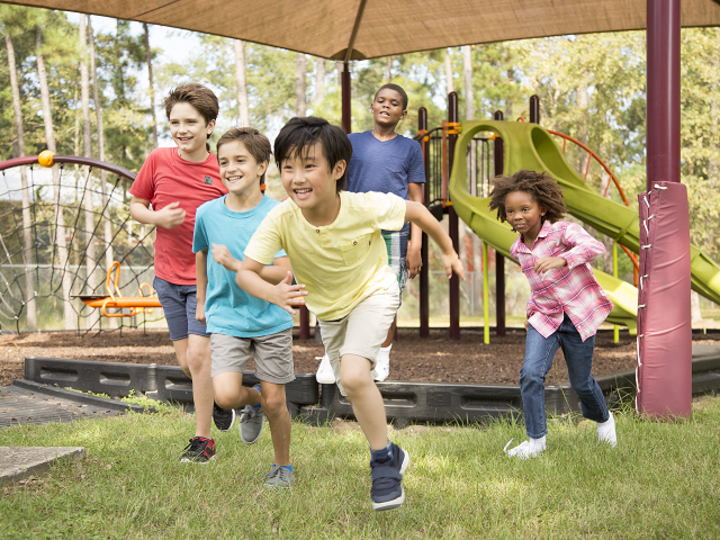 Multi-ethnic group of school children playing on school playground. The group of friends excitedly run toward the next outdoor activity. 