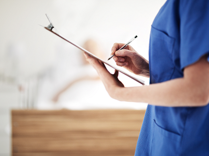 Female nurse holding report paperwork on clipboard.